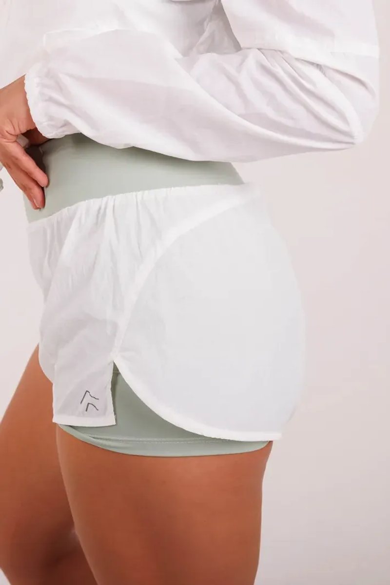 Cadence Running Short na cor Branco, vista de frente. Moda fitness AERA, feita no Brasil.
