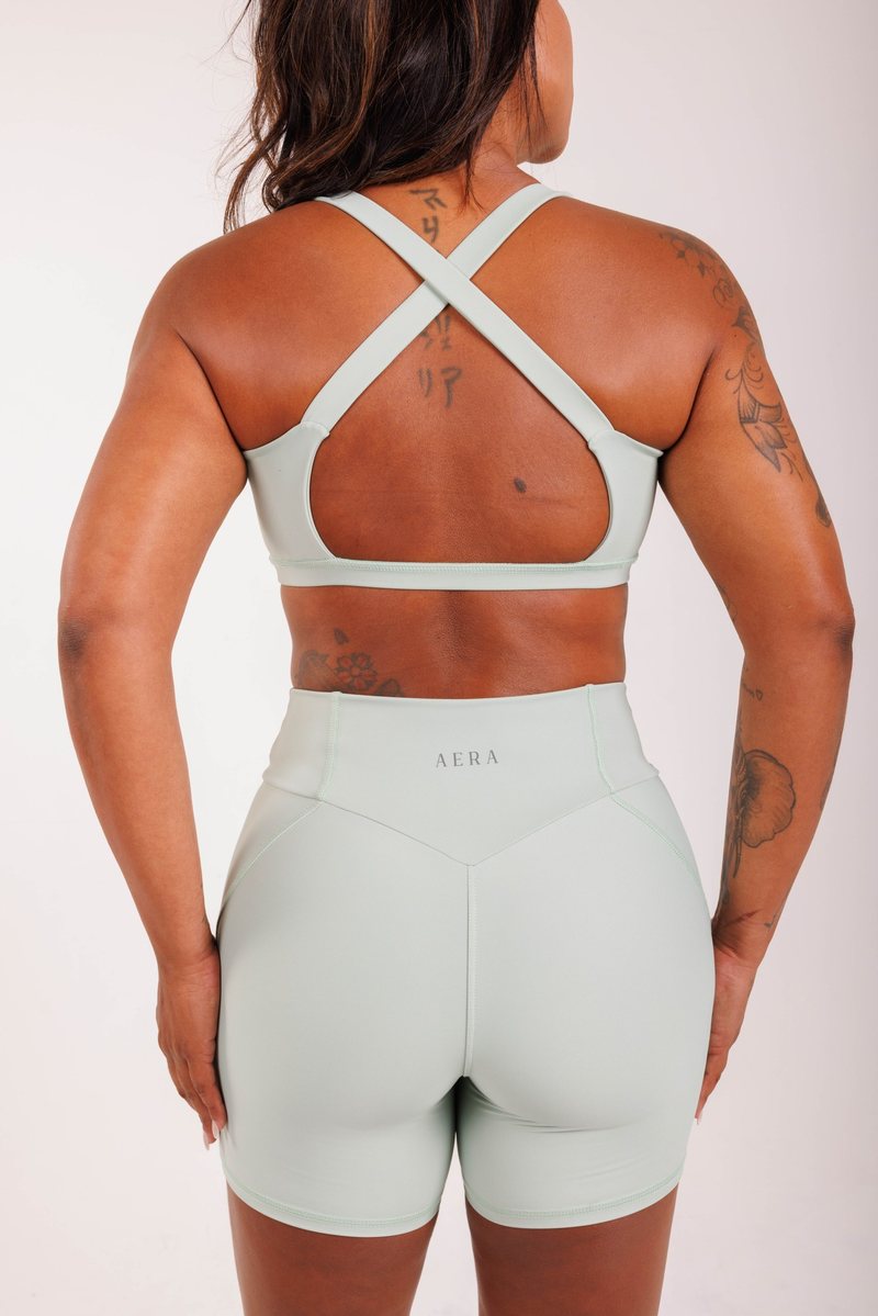 Crossover Bra na cor Verde sálvia, vista lateral. Moda fitness AERA, feita no Brasil.