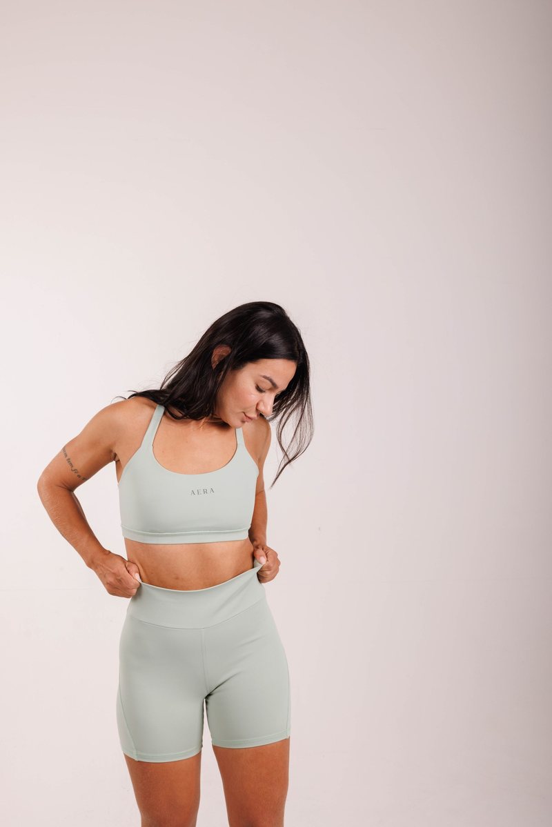 Meridian Biker Short na cor Verde sálvia, em movimento. Moda fitness AERA, feita no Brasil.
